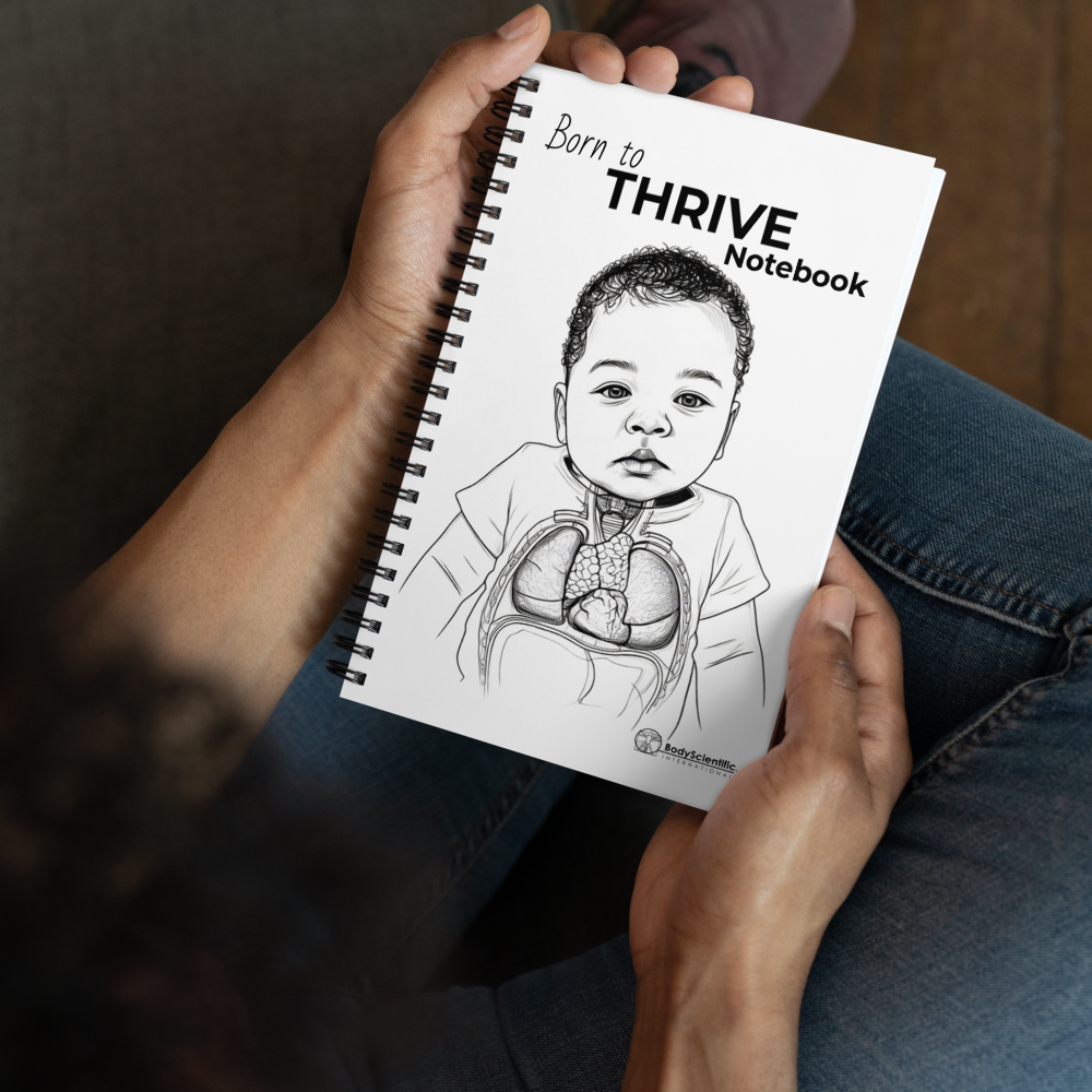 Person holding a 'Born to THRIVE Notebook' with a child's illustration on the cover.